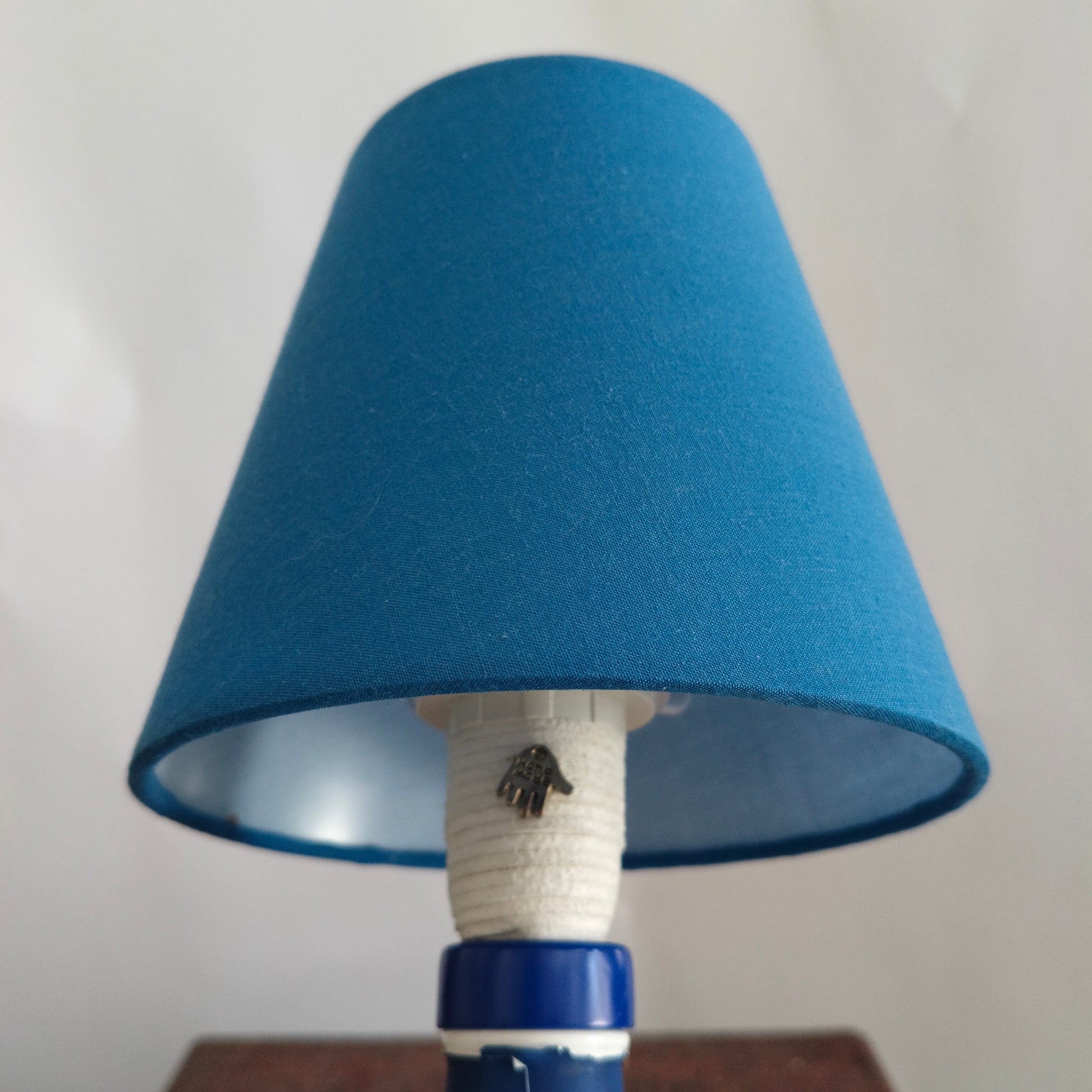 Close-up of blue lampshade and suede-wrapped stem with Jolly Roger charm