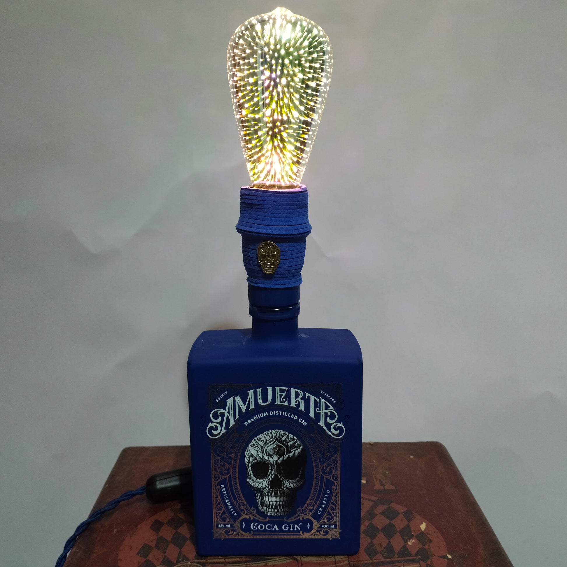 Skull emblem and suede wrap on LAMuerteAzuL bottle lamp